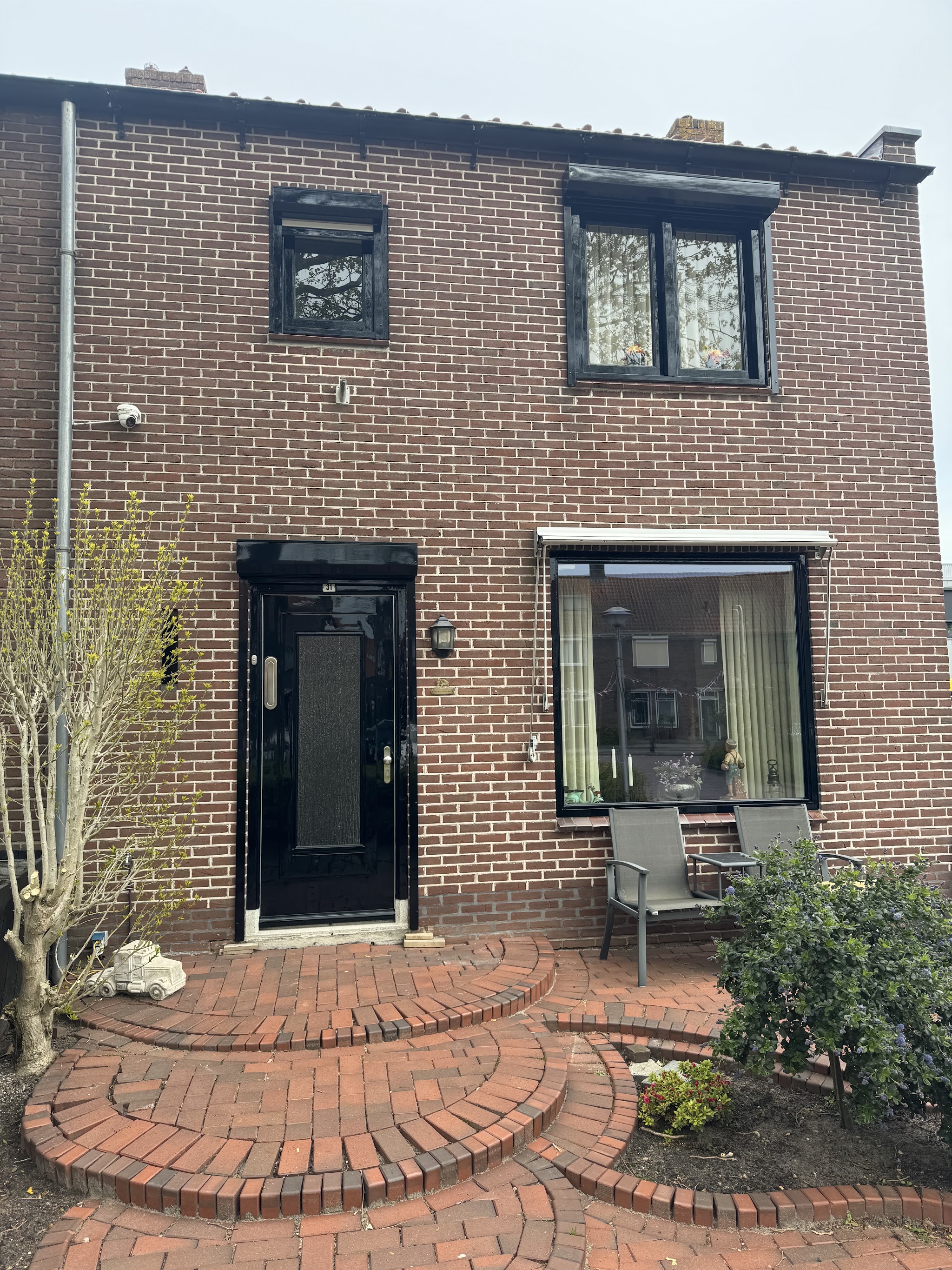 Bakstenen woning met zwart gelakte voordeur en kozijnen