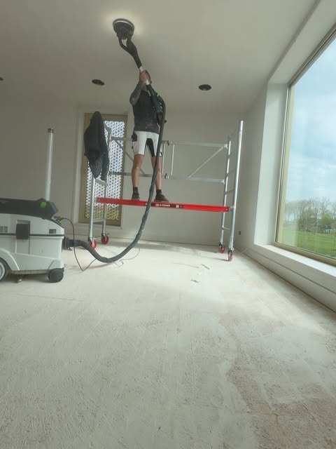 Plafond wordt geschuurd met een langnekschuurmachine vanaf een rolsteiger