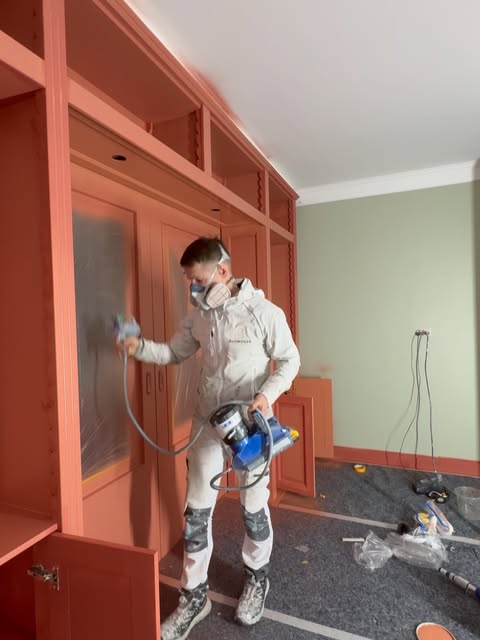 Schilder spuit een terracotta inbouwkast met een airless spuit